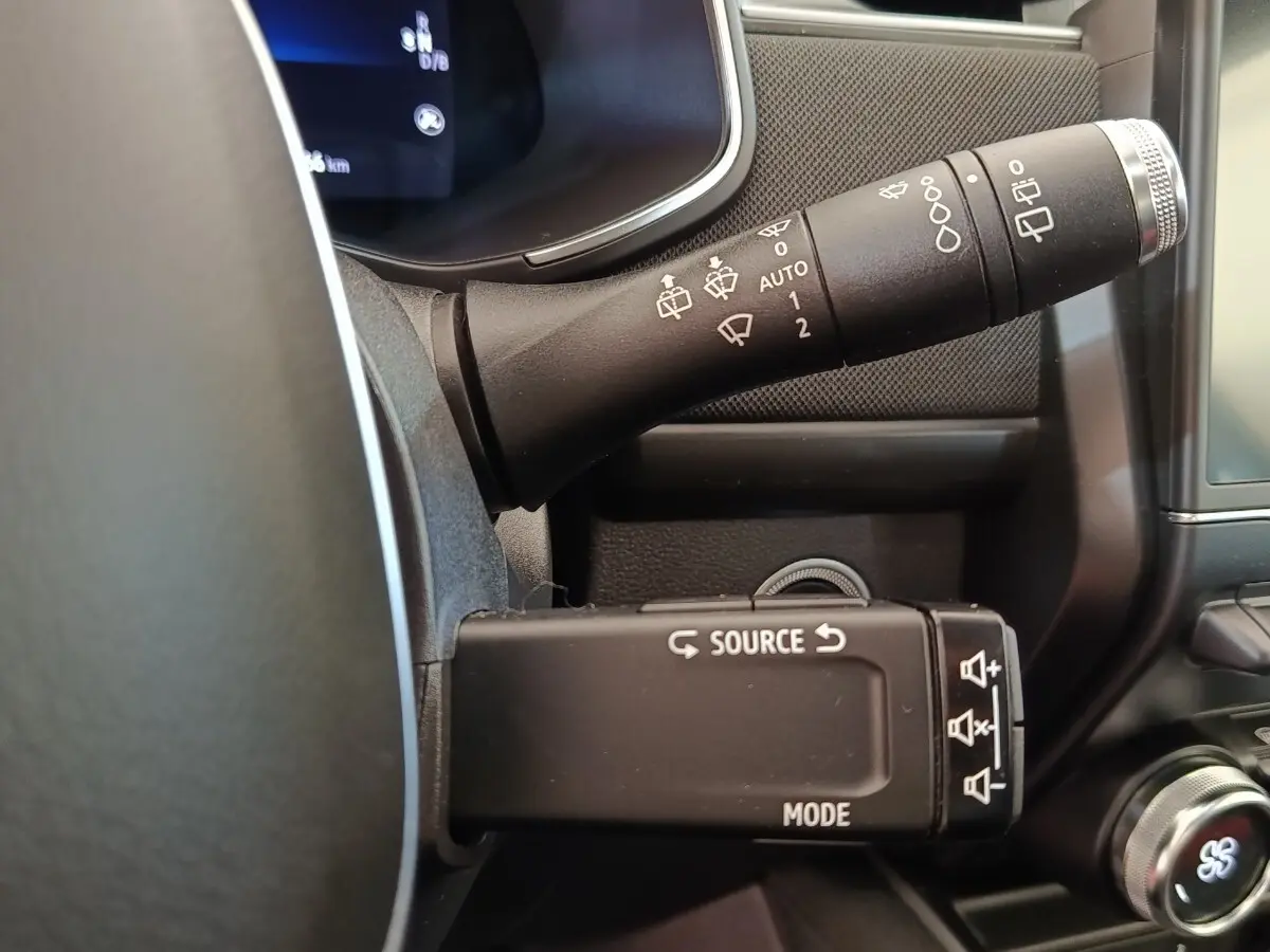Détail du commodo noir multifonctions à gauche du volant dans l'habitacle de la Renault ZOE blanche 2021.