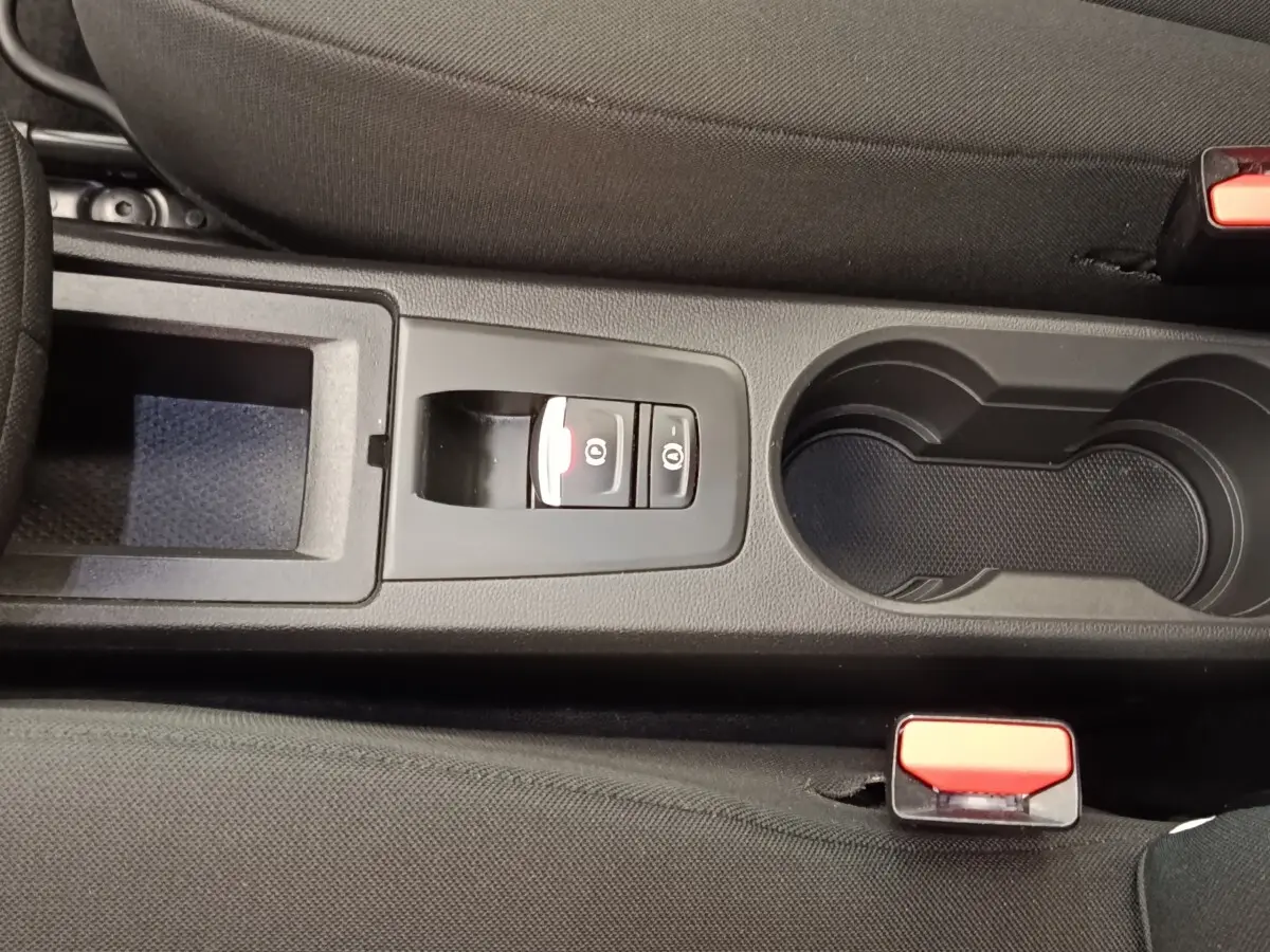 Vue rapprochée de la console centrale noire de la Renault ZOE blanche 2021 avec frein à main électrique et porte-gobelets.
