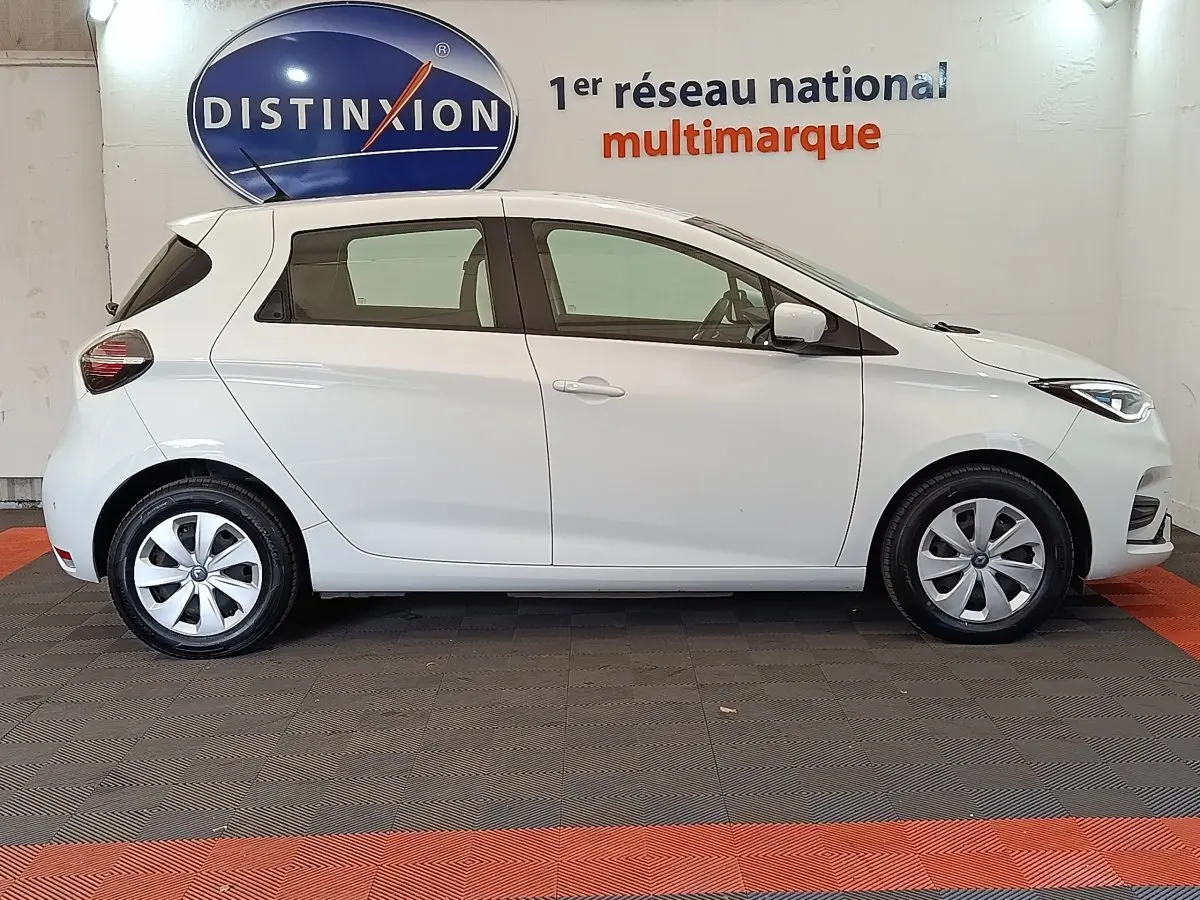 Profil droit d'une Renault ZOE Business Rev R110 blanche de 2021, avec jantes alliage et feux LED visibles.