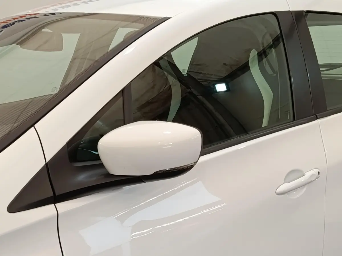 Gros plan sur le rétroviseur et la porte côté gauche d'une Renault ZOE blanche, intérieur visible à travers la vitre.