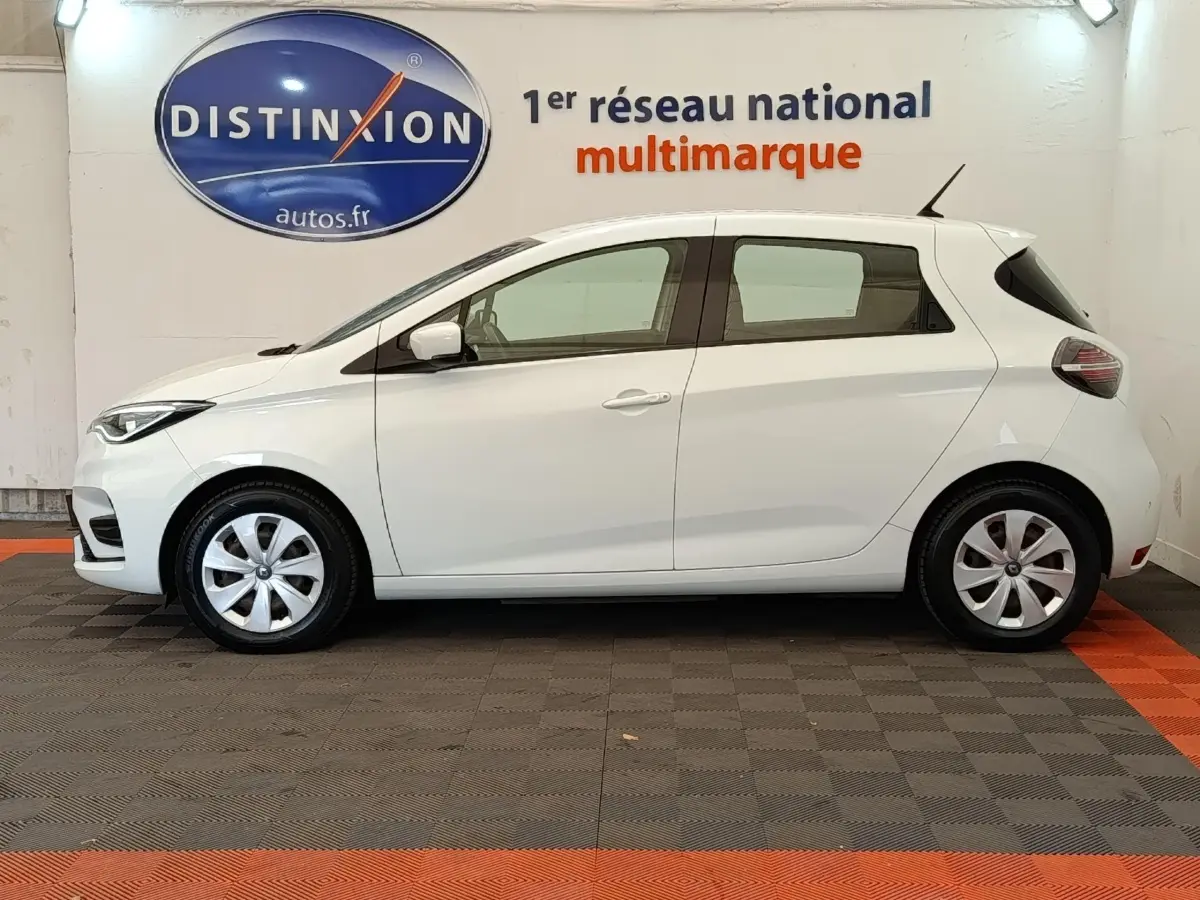 Profil côté gauche d'une Renault ZOE blanche 2021 Business Rev R110, avec jantes alliage et feux arrière LED visibles.