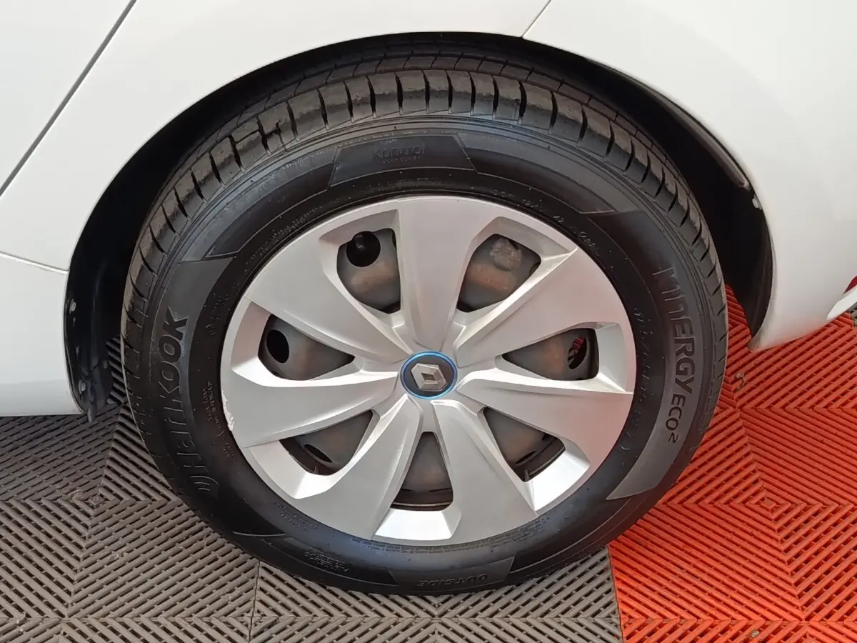Gros plan sur la roue arrière droite blanche d'une Renault ZOE 2021 avec jante en alliage et logo Renault central.