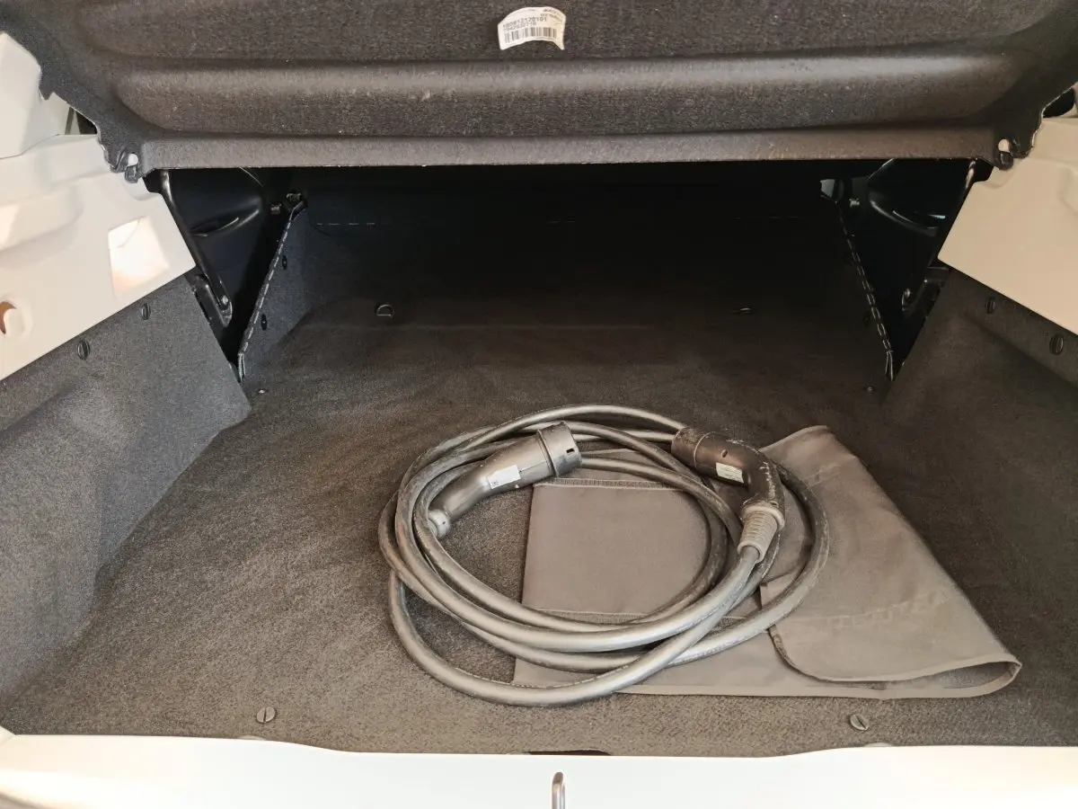 Coffre ouvert d’une Renault ZOE blanche 2021, vue arrière montrant un câble de recharge électrique enroulé.