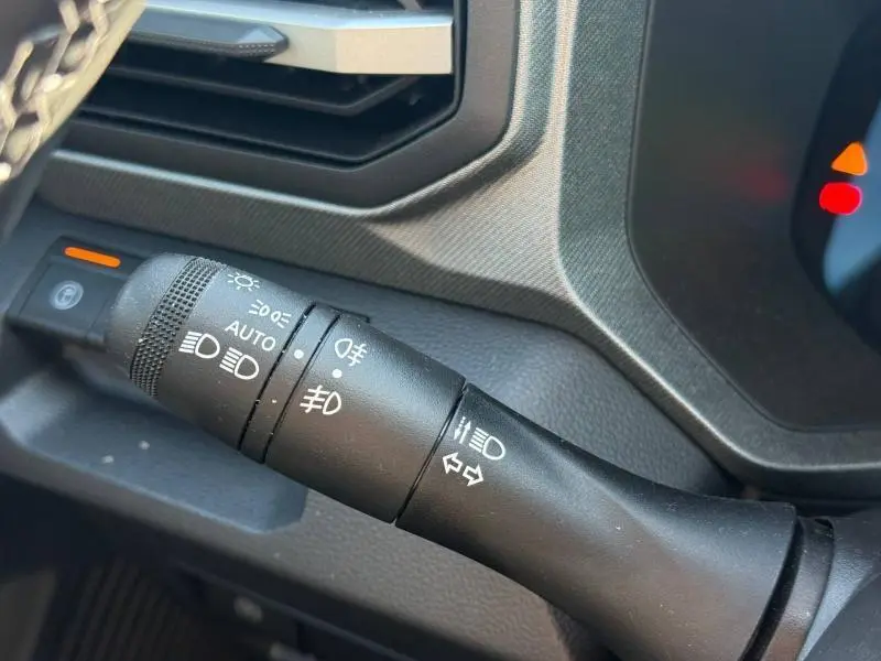 Gros plan sur la commande des phares et clignotants du Dacia Bigster gris Schiste, intérieur noir texturé.