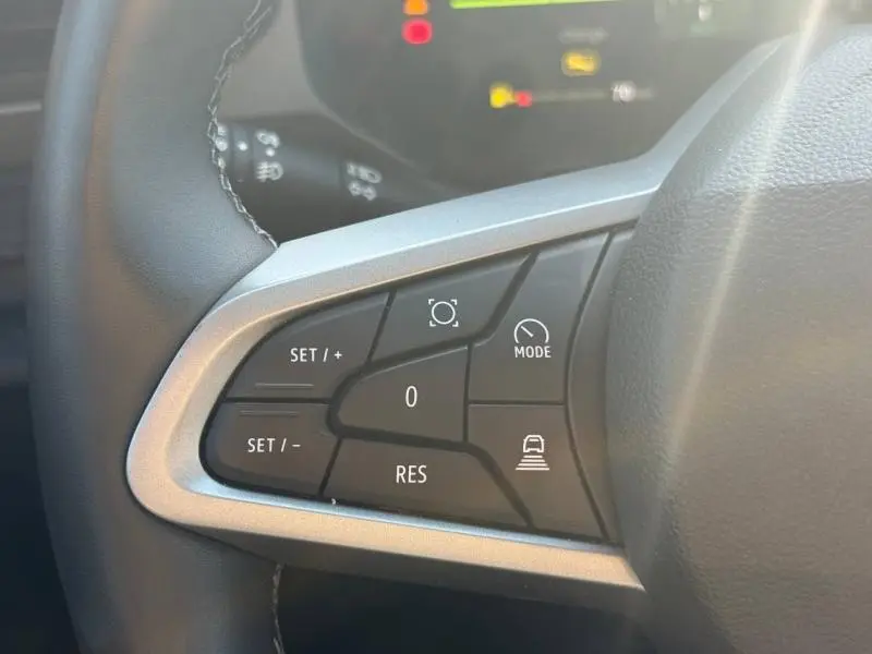 Gros plan sur les commandes multifonctions noires du volant du Dacia Bigster gris Schiste, avec boutons de régulateur et mode.