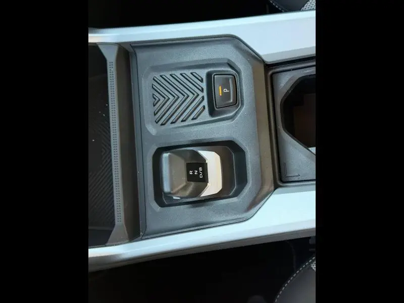 Vue rapprochée de la console centrale grise du Dacia Bigster 2025, montrant le levier de vitesses automatique et le bouton de stationnement.