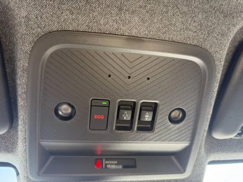 Vue en contre-plongée du panneau de commande de toit intérieur gris avec bouton SOS rouge et commandes d'ouverture de toit sur Dacia Bigster.