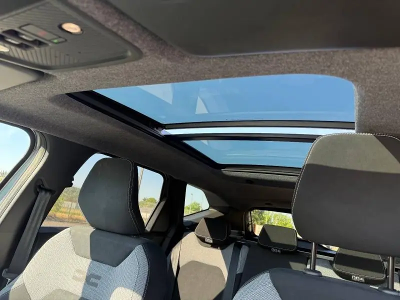 Vue intérieure du Dacia Bigster gris Schiste montrant le toit panoramique et les sièges avant et arrière en tissu.