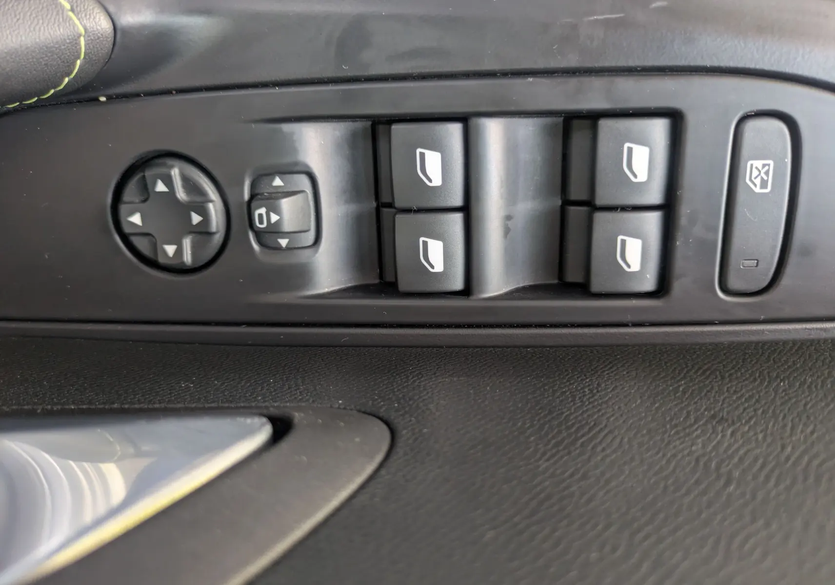 Gros plan sur les commandes de lève-vitres et réglage des rétroviseurs côté conducteur de la Peugeot 208 Hybrid 145 GT.