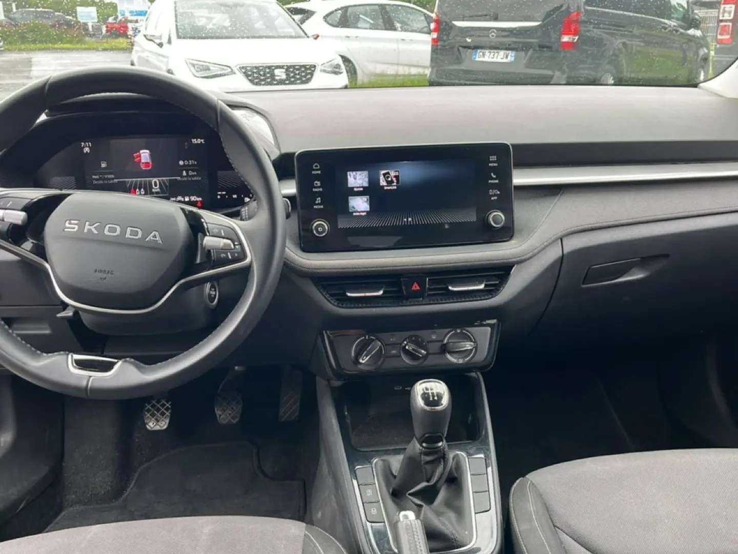 Vue intérieure avant de la Skoda Fabia noire 2025, volant multifonction, écran tactile et levier de vitesse manuel visibles.
