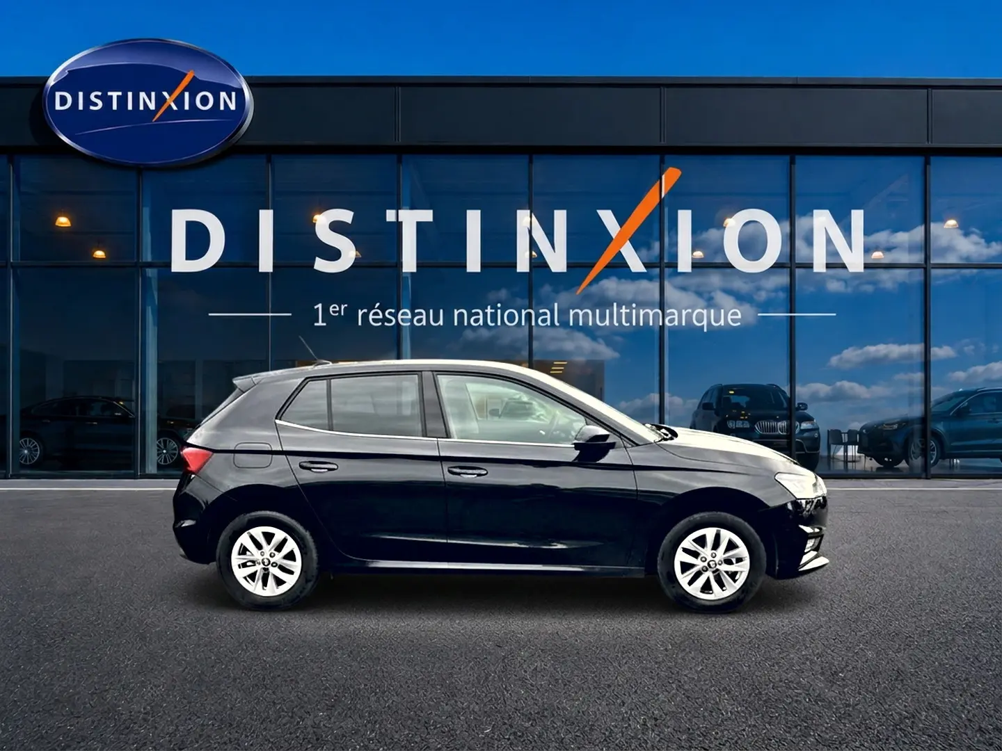 Profil côté gauche d'une Skoda Fabia noire 2025 garée devant une vitrine avec logo Distinxion.