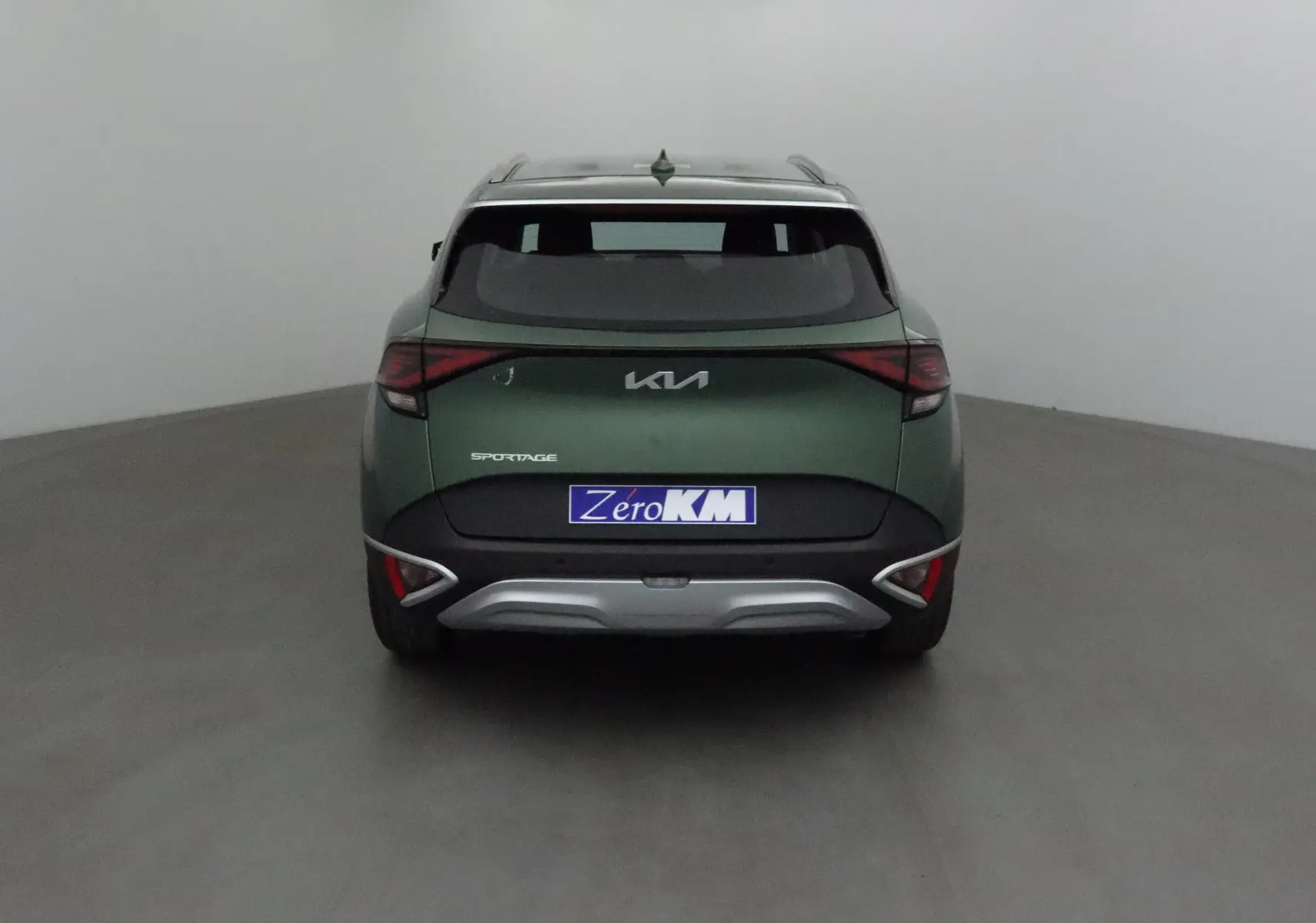 Vue arrière d'un KIA Sportage vert Borneo 2025 avec feux LED et logo KIA moderne sur fond neutre.