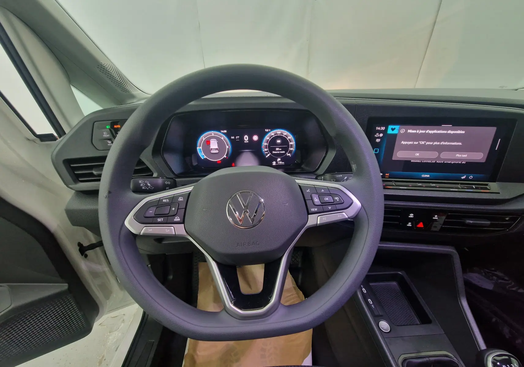Vue centrée sur le volant et le tableau de bord numérique du Volkswagen Caddy Maxi blanc, mettant en valeur l'écran tactile et les commandes intégrées.