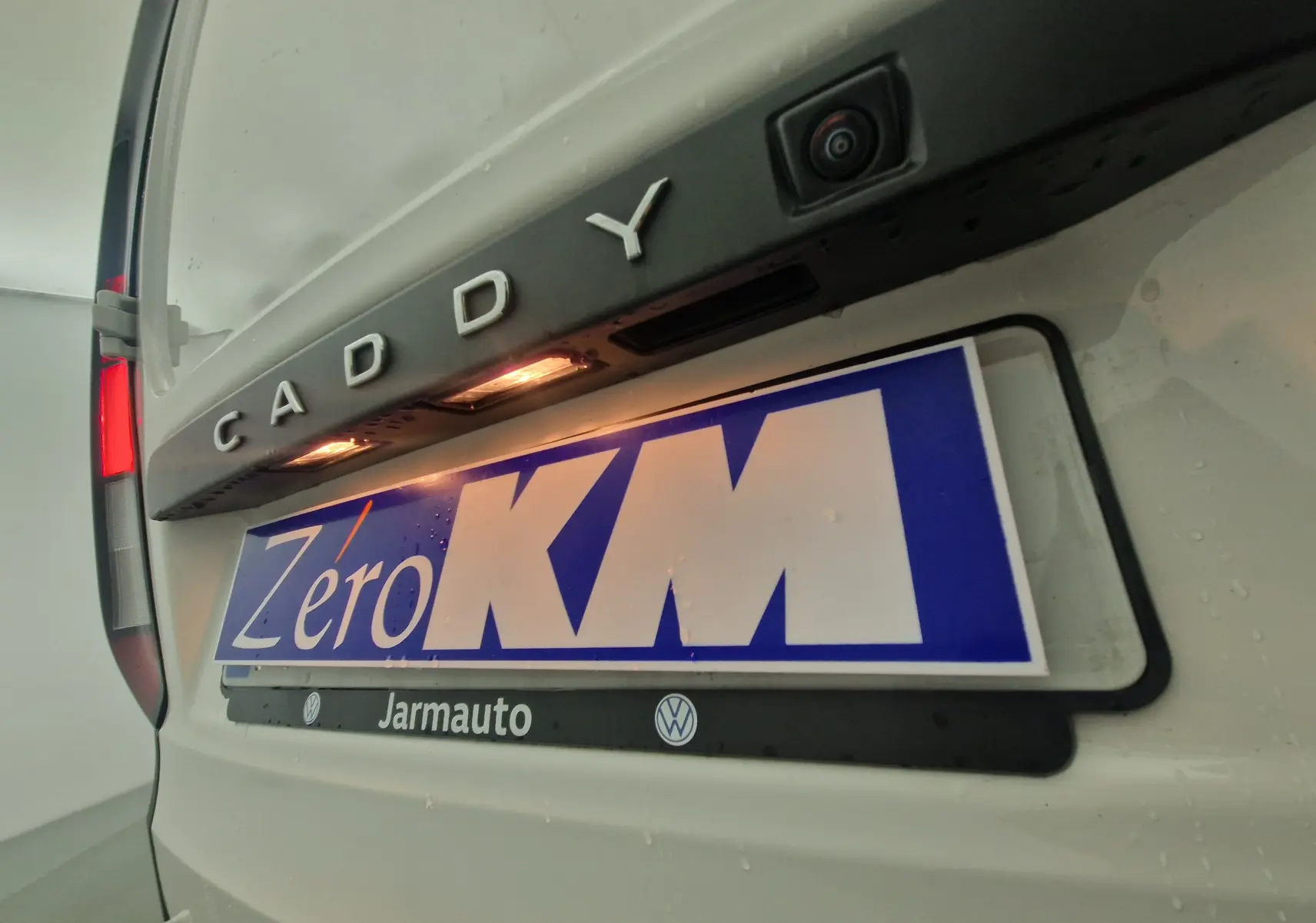 Gros plan arrière sur la plaque et la caméra de recul du Volkswagen Caddy Maxi blanc avec éclairage de plaque.