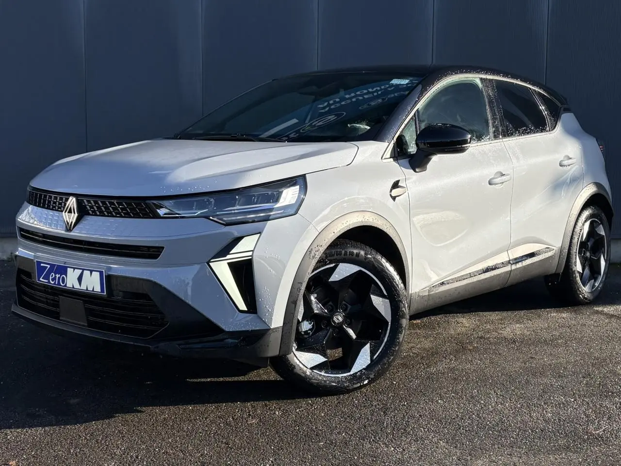 Vue 3/4 avant droit du Renault Captur 2025 gris Rafale avec toit noir et jantes aluminium noires distinctives.