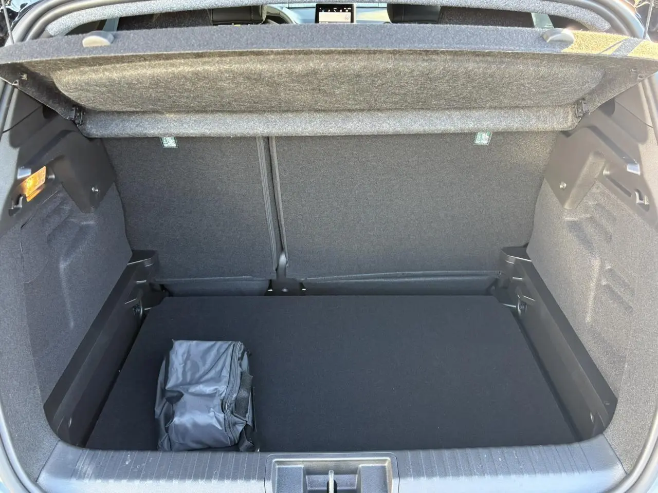 Vue intérieure du coffre ouvert du Renault Captur gris Rafale, montrant un rangement avec sac noir posé.
