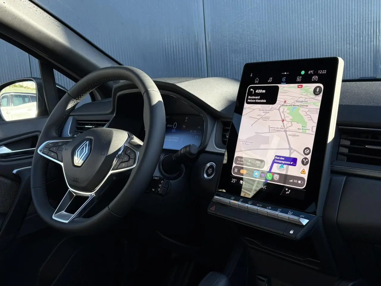 Vue intérieure côté conducteur du Renault Captur 2025 avec volant noir et écran tactile vertical 10,4 pouces affichant la navigation.