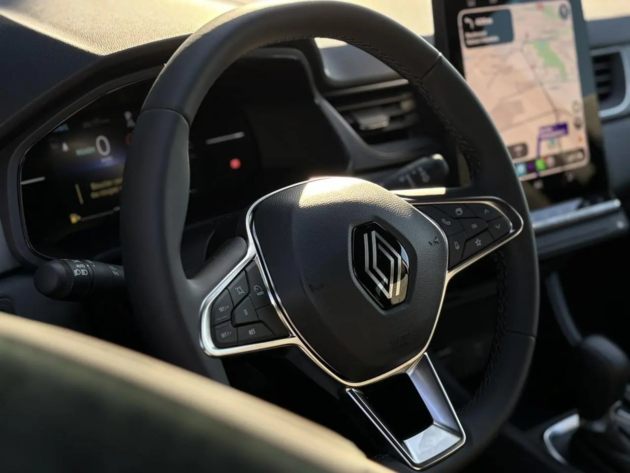 Vue rapprochée du volant noir de la Renault Captur 2025 avec commandes intégrées et écran tactile en arrière-plan.