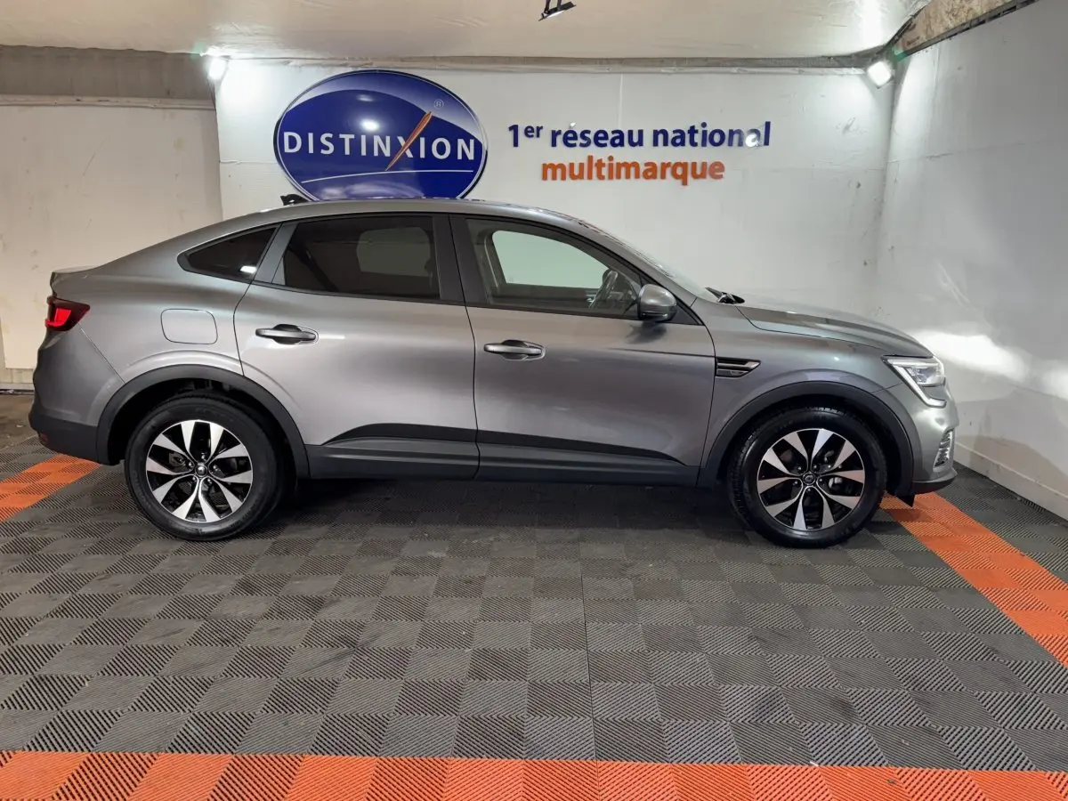 Profil côté gauche d'un Renault Arkana Business E-TECH 145 gris foncé, SUV hybride avec jantes alliage et lignes fluides.