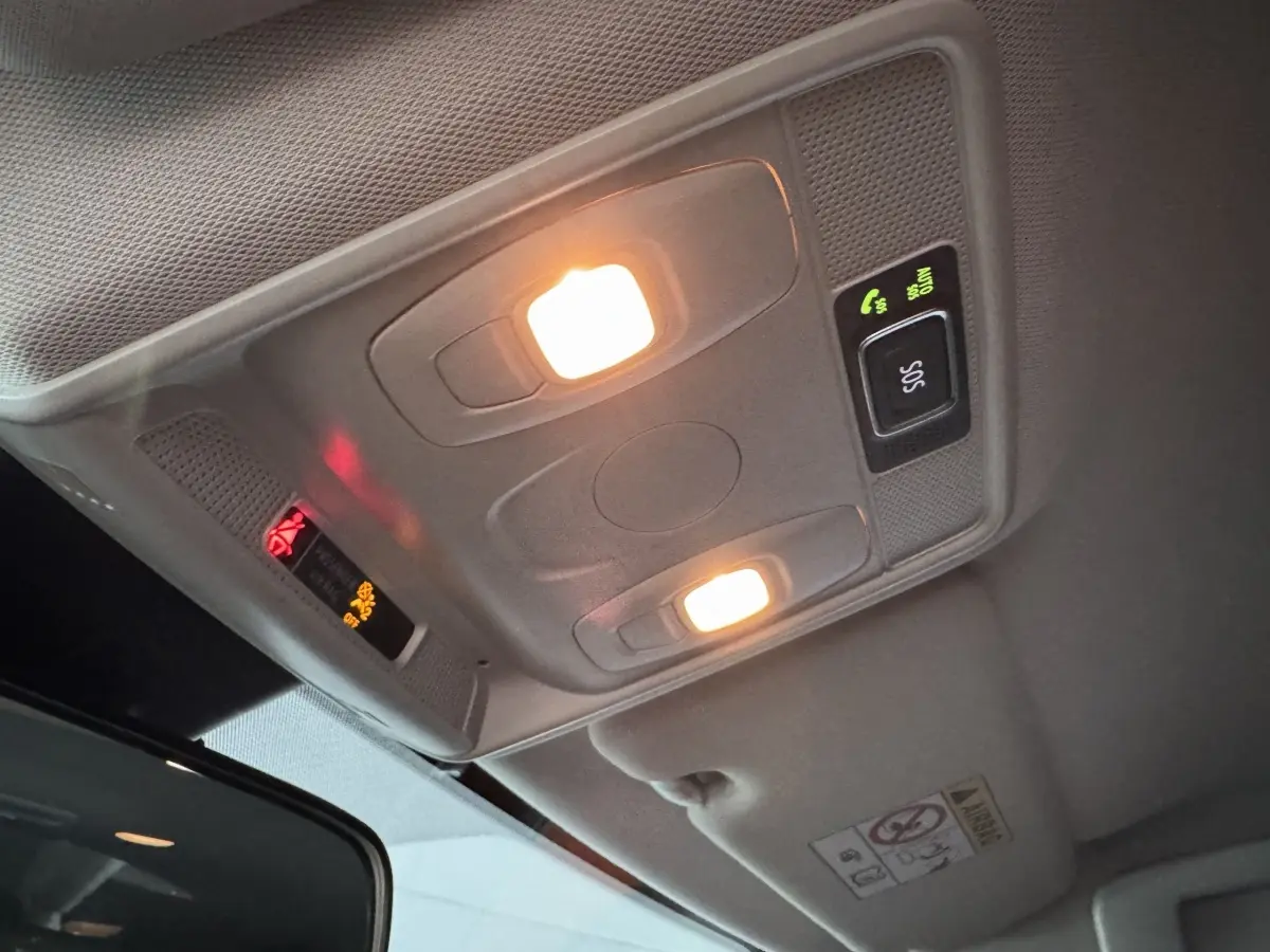 Plafonnier intérieur allumé avec boutons SOS et appels, vue en légère contre-plongée dans Renault Arkana gris foncé.