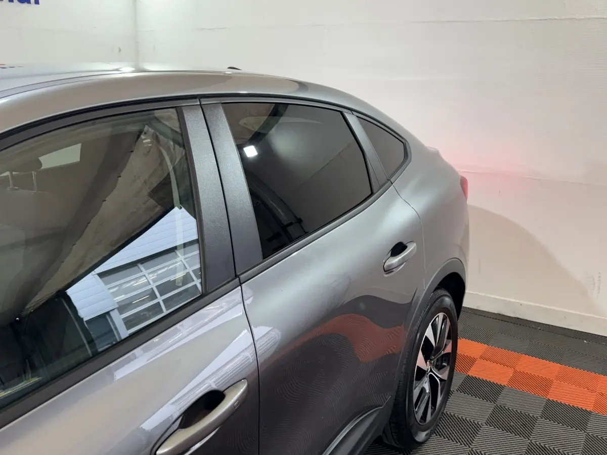 Vue côté droit arrière du Renault Arkana Business E-TECH gris foncé, mettant en valeur la porte et la roue arrière.