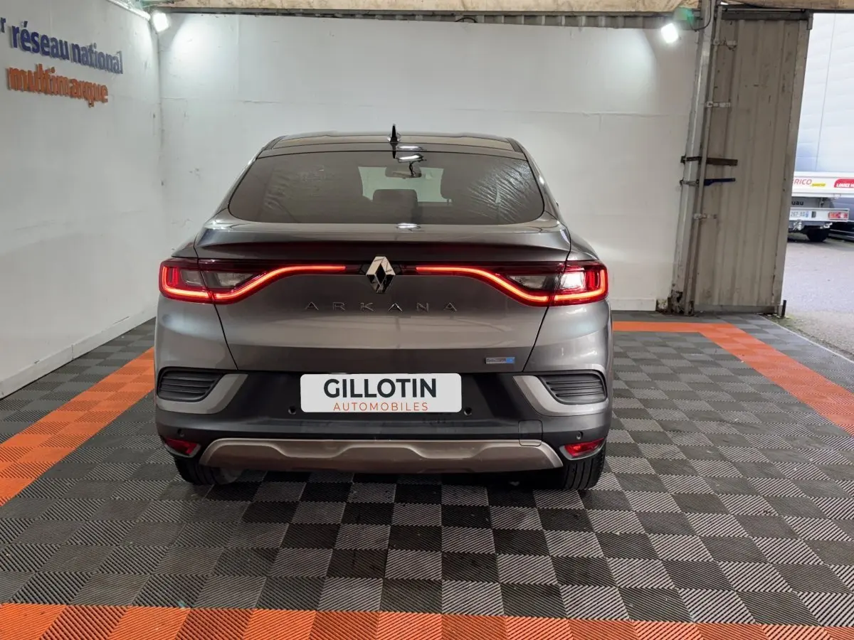 Vue arrière d'une Renault Arkana Business E-TECH 145 gris foncé avec feux LED allumés dans un garage.