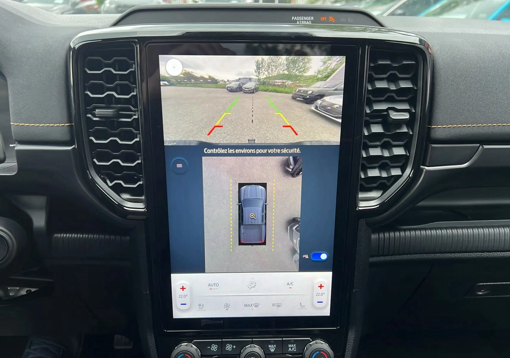 Vue intérieure du tableau de bord du Ford Ranger gris carbone 2025 avec écran tactile affichant la caméra 360° et l'aide au stationnement.