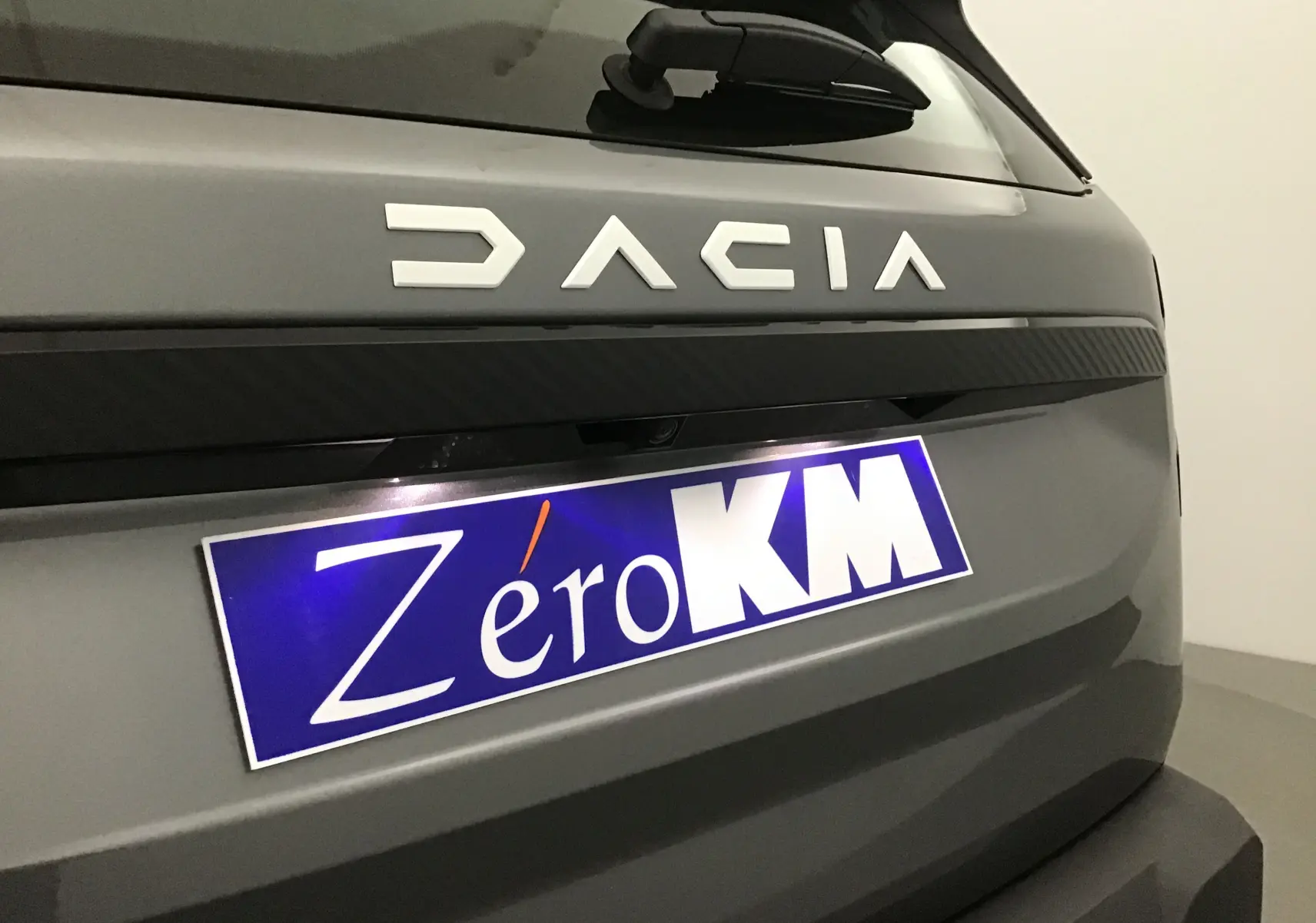 Gros plan sur l'arrière gris schiste du Dacia Bigster 2025 avec logo et plaque Zéro KM visible.