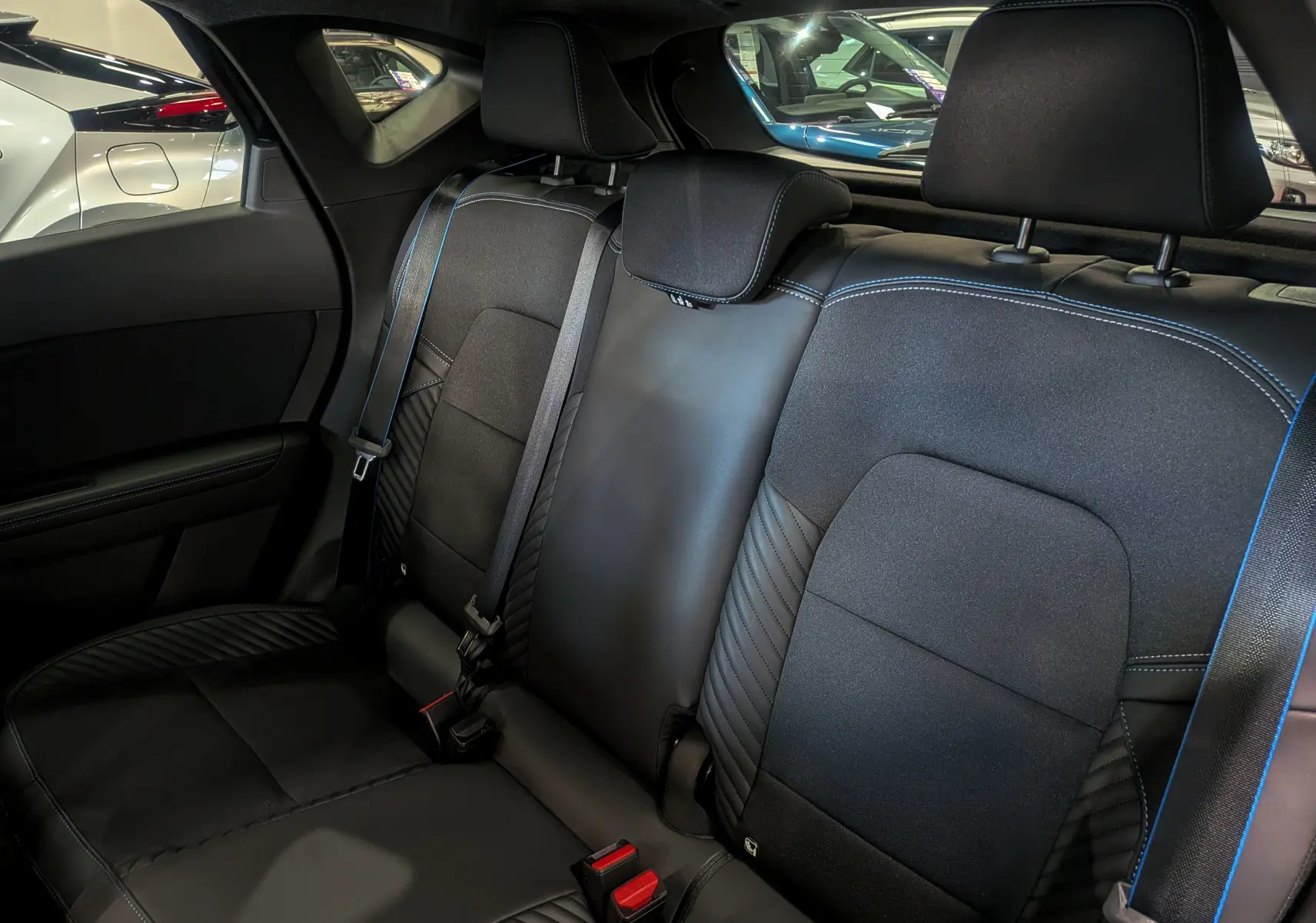 Vue intérieure sur les sièges arrière noirs avec surpiqûres bleues du Renault Captur E-TECH Full Hybrid 2025 esprit Alpine.