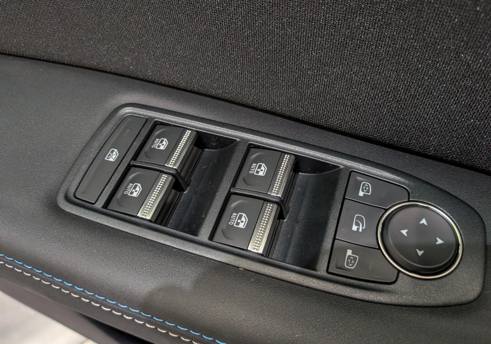 Panneau de commandes des vitres électriques et rétroviseurs sur la porte intérieure d'un Renault Captur noir étoilé 2025.