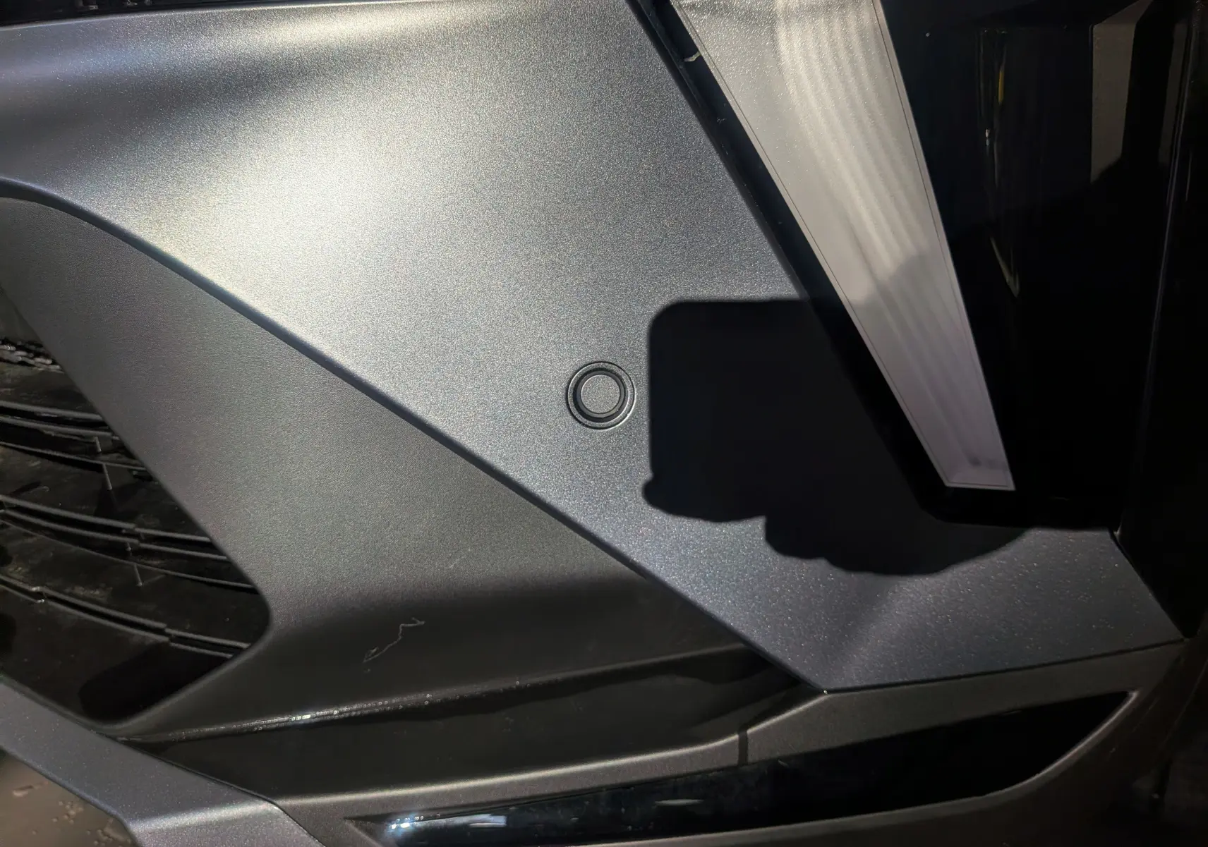 Gros plan sur le pare-chocs avant noir étoilé du Renault Captur E-TECH Full Hybrid 160 CH esprit Alpine, avec capteur de stationnement visible.