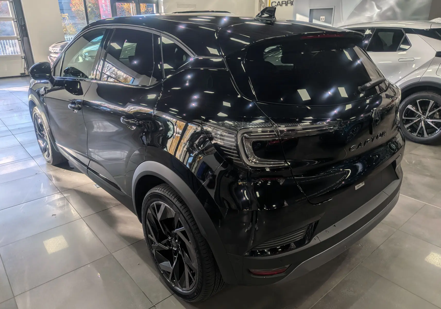 Vue 3/4 arrière droite du Renault Captur E-TECH Full Hybrid noir étoilé, soulignant ses jantes noires et ses feux arrière LED.
