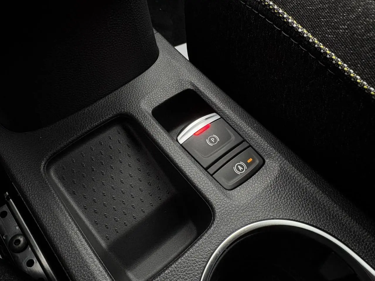 Gros plan sur la console centrale noire du Renault Captur 2025, avec frein à main électrique et bouton auto-hold.