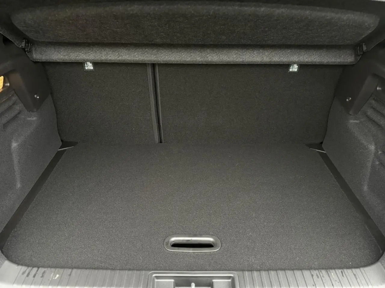 Coffre vide du Renault Captur 2025, vue intérieure arrière, avec plancher de coffre mobile et revêtement noir.