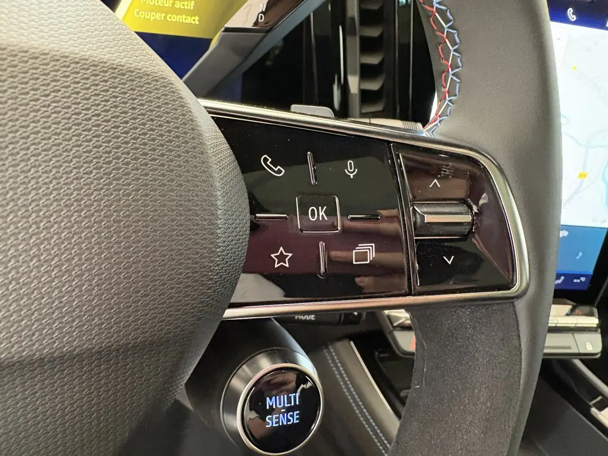 Gros plan sur le volant cuir-suède avec commandes multifonctions et écran tactile du tableau de bord du Renault Espace blanc 2025.