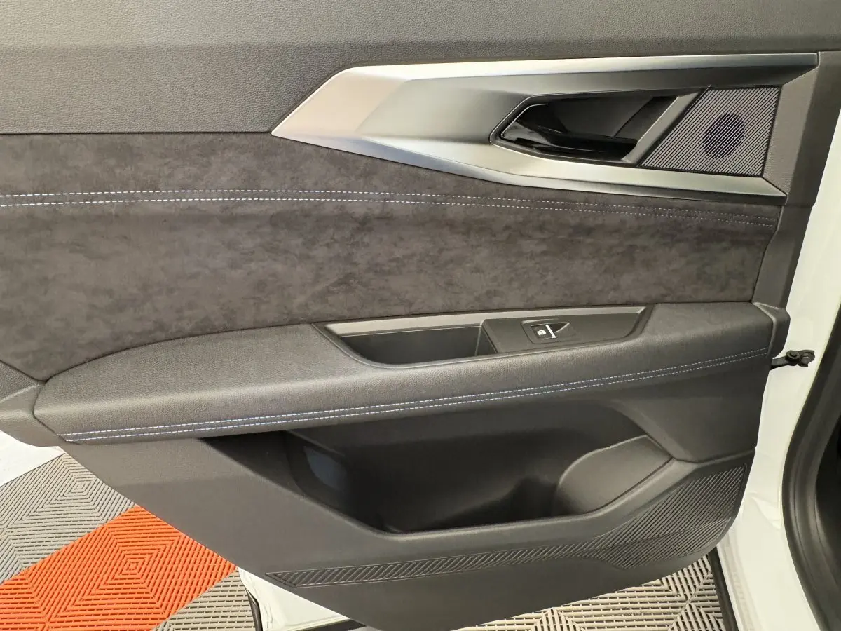 Vue rapprochée de la porte intérieure côté gauche du Renault Espace blanc, avec garniture noire et surpiqûres bleues.