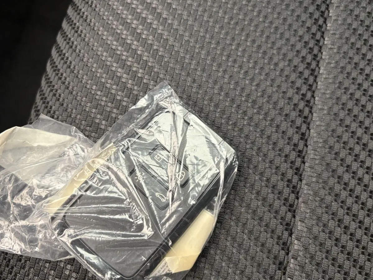 Télécommande Renault Espace 2025 en plastique transparent posée sur un siège tissu gris à motifs géométriques.