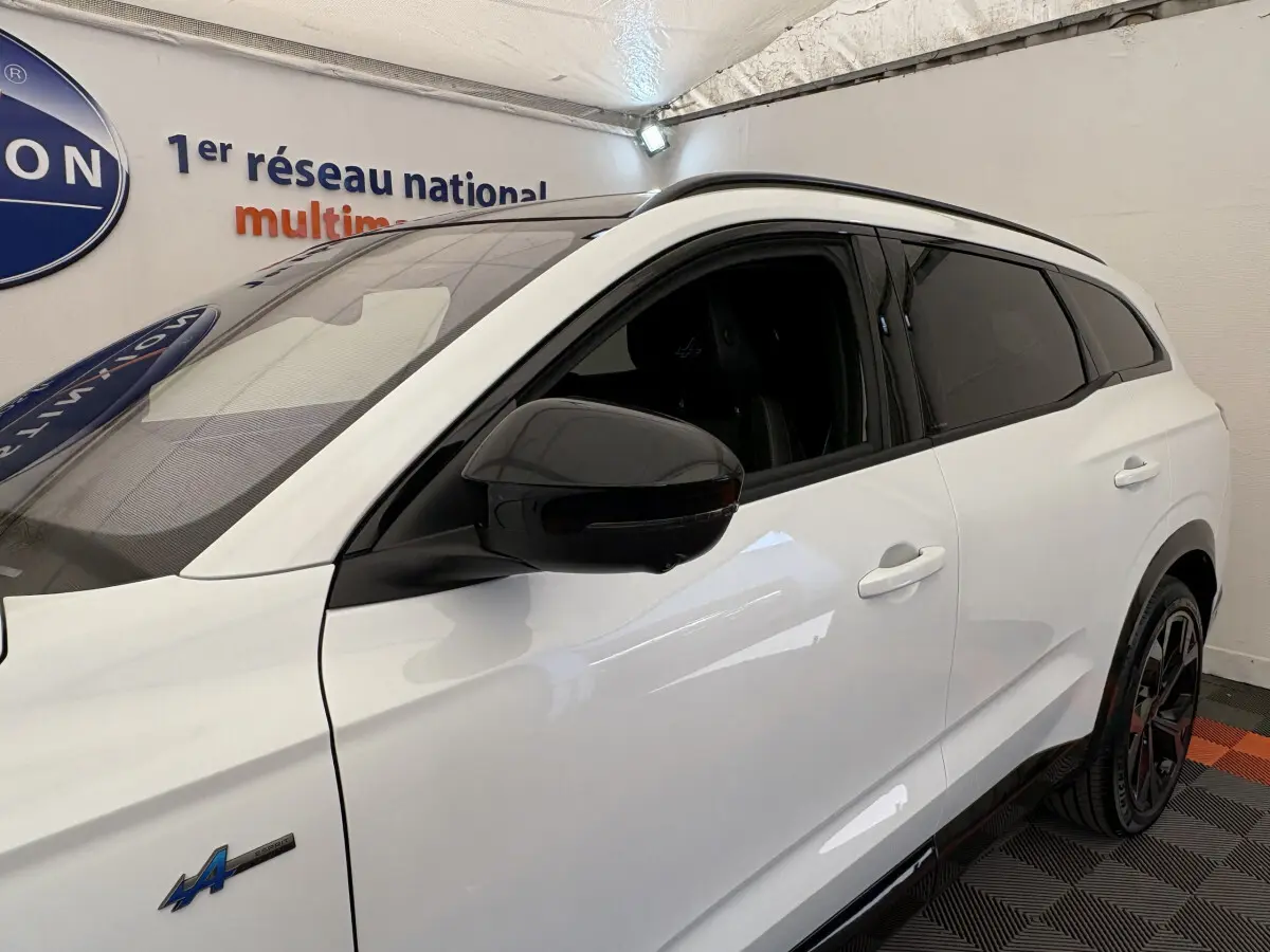 Vue côté gauche avant d'un Renault Espace blanc esprit Alpine 7 places avec rétroviseur noir et vitres teintées.