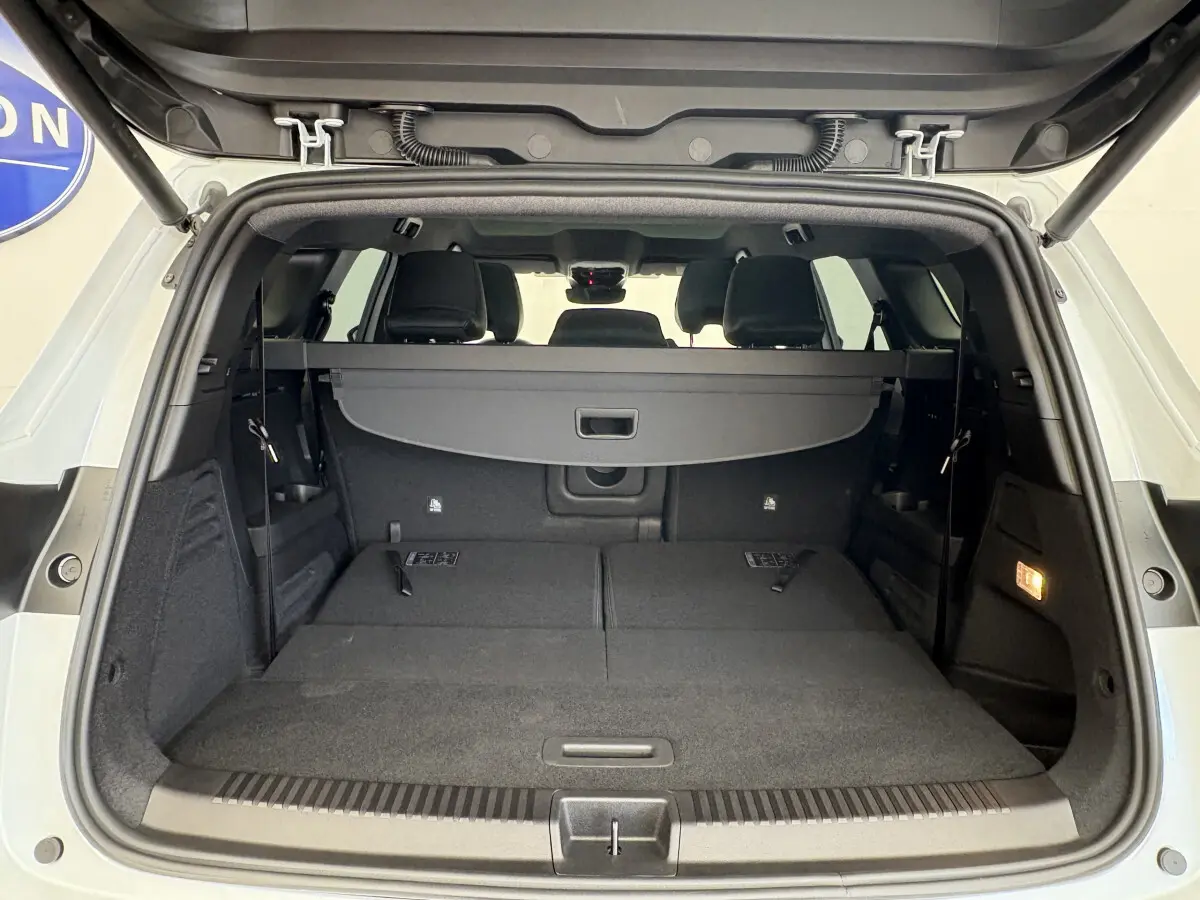 Coffre ouvert vu de l'arrière d'un Renault Espace blanc 2025 avec sièges rabattus et cache-bagages noir.