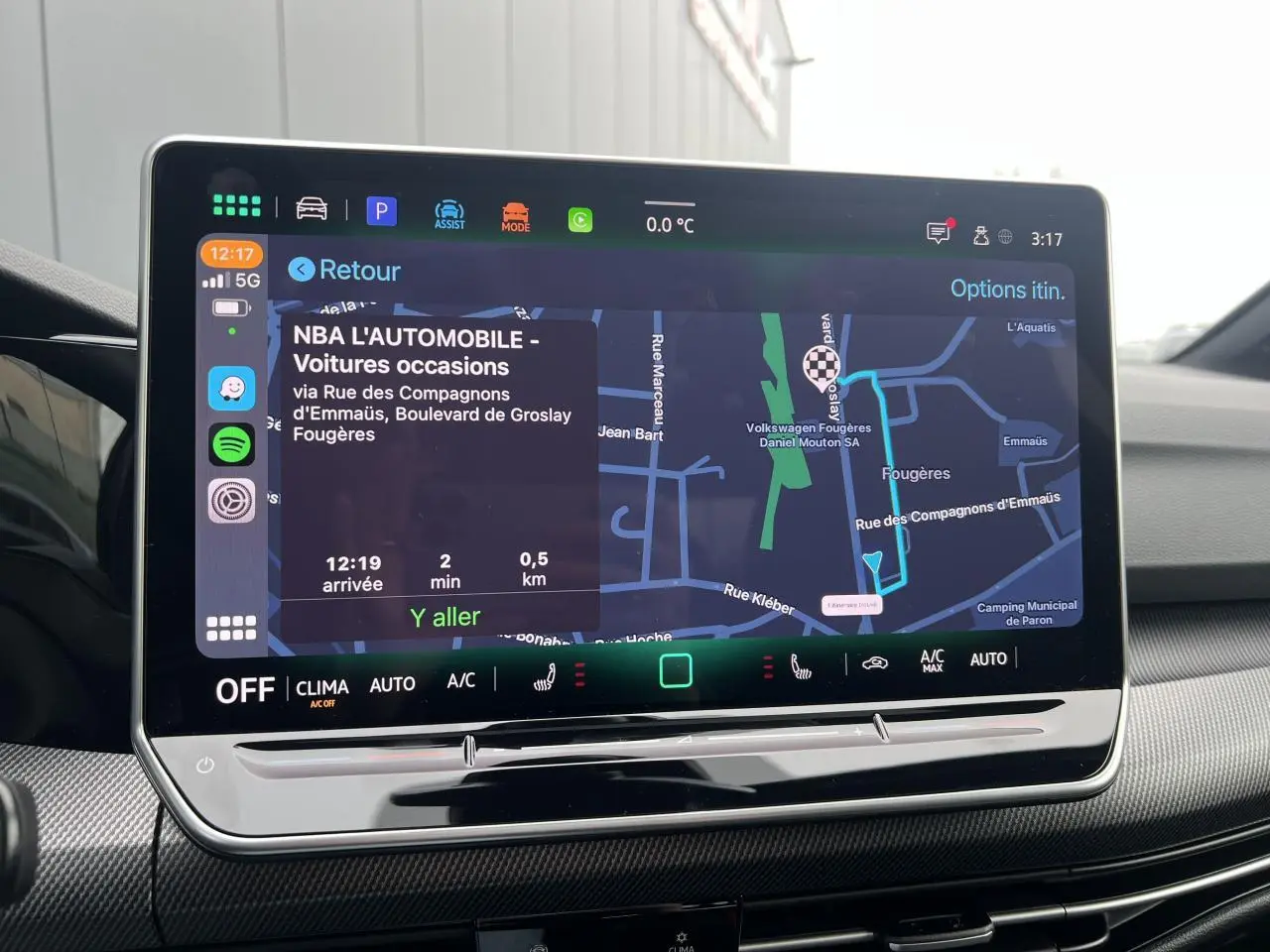 Écran tactile intérieur de la Volkswagen Golf VIII noir, affichant le GPS avec itinéraire et commandes climatisation.