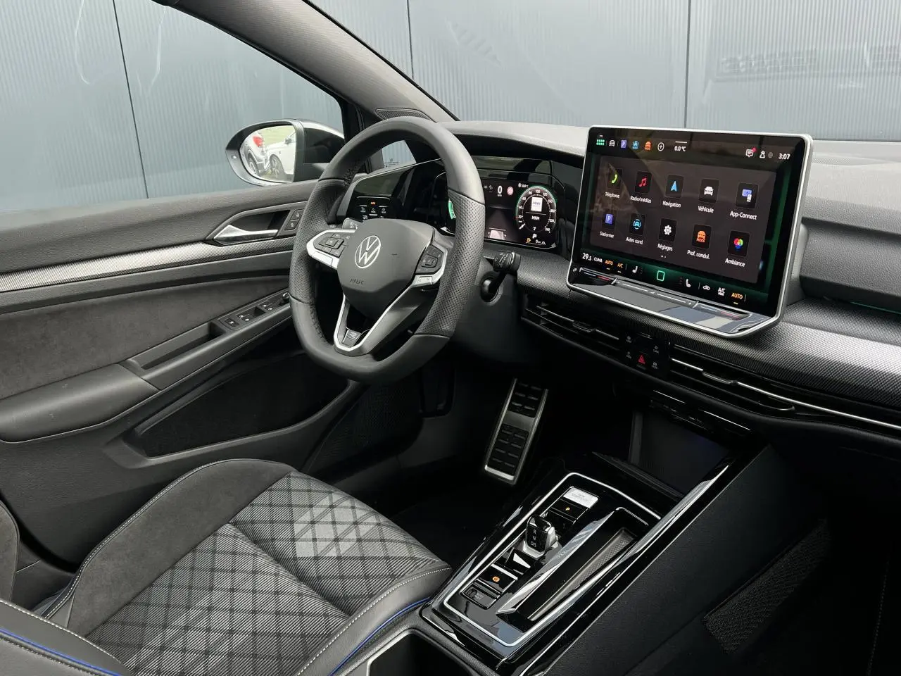 Vue intérieure côté conducteur de la Volkswagen Golf VIII R-Line 2026, avec tableau de bord numérique et sellerie noire à motifs.