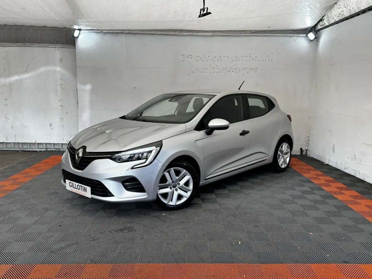 Renault Clio Business TCe 100 2020 gris clair vue 3/4 avant droit dans un garage avec sol noir et bandes orange.