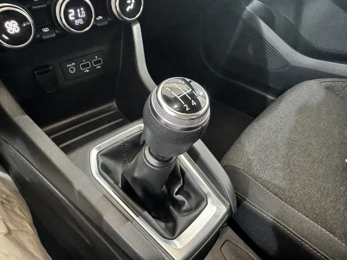 Gros plan sur le levier de vitesse manuel noir et argenté dans l'habitacle sombre de la Renault Clio Business TCe 100.