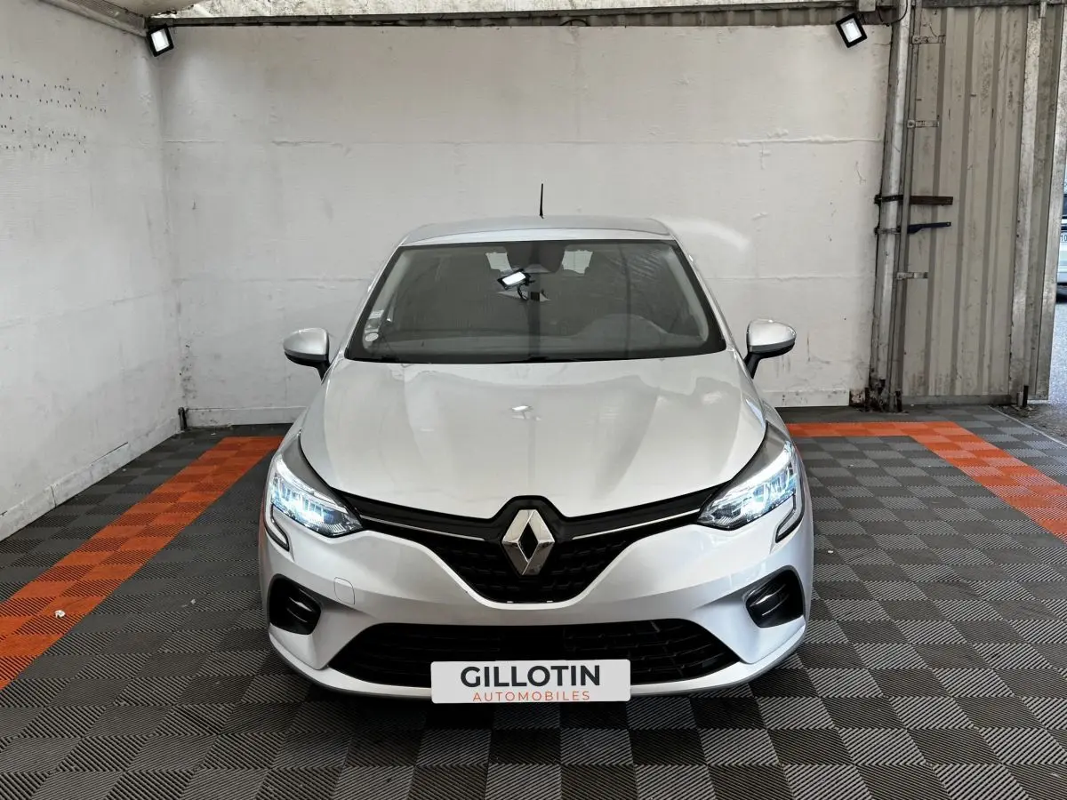 Vue frontale d'une Renault Clio Business TCe 100 gris clair avec phares LED allumés dans un garage.