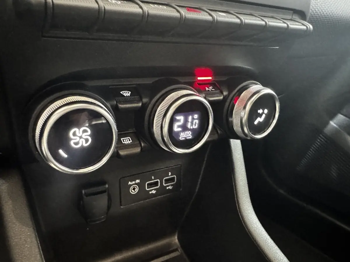 Gros plan sur les commandes de climatisation et les ports USB d’une Renault Clio Business TCe 100 gris clair, intérieur noir.