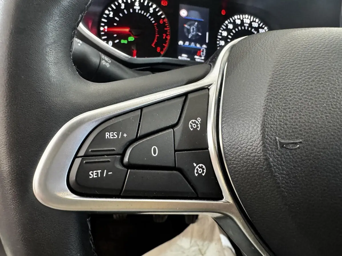 Gros plan sur le volant noir de la Renault Clio 2020, avec commandes de régulateur de vitesse visibles à gauche.