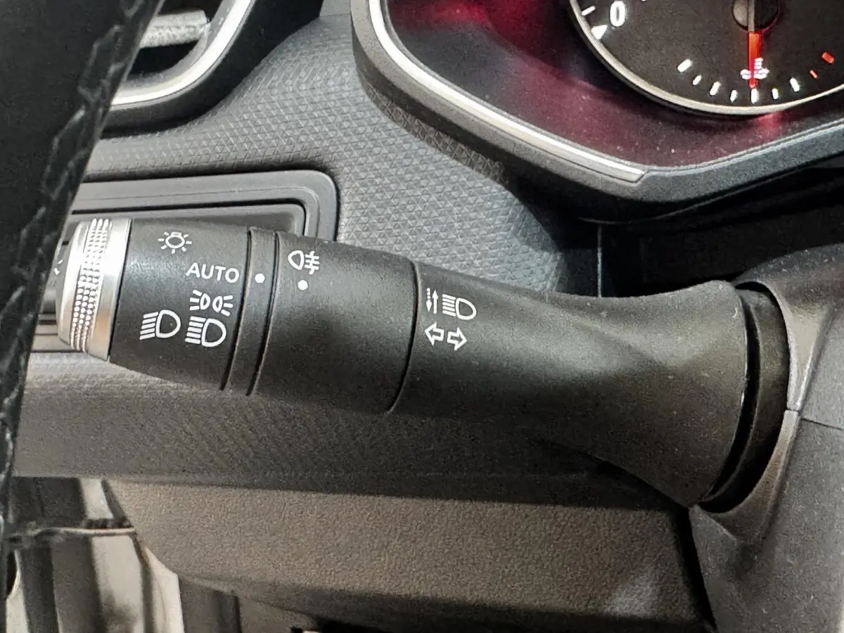 Gros plan sur la commande des phares et clignotants du tableau de bord d’une Renault Clio Business gris clair de 2020.