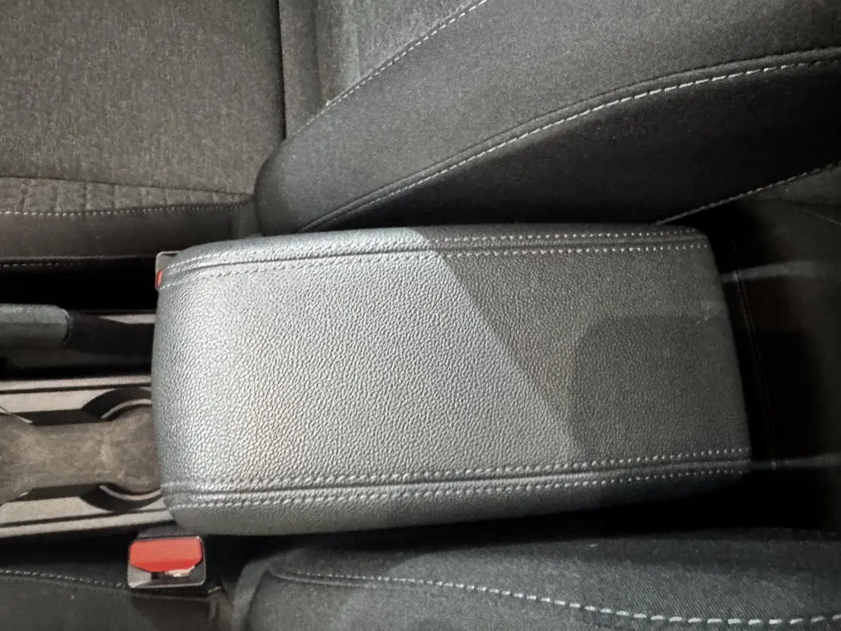 Gros plan sur l'accoudoir central en cuir synthétique gris foncé de la Renault Clio Business TCe 100, intérieur tissu noir.