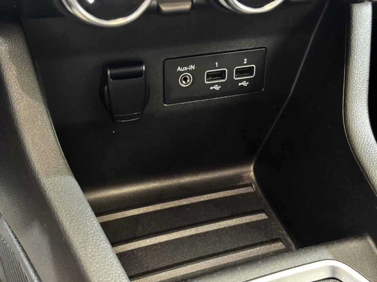 Gros plan sur la console centrale noire de la Renault Clio Business TCe 100 avec ports USB et prise Aux-In.