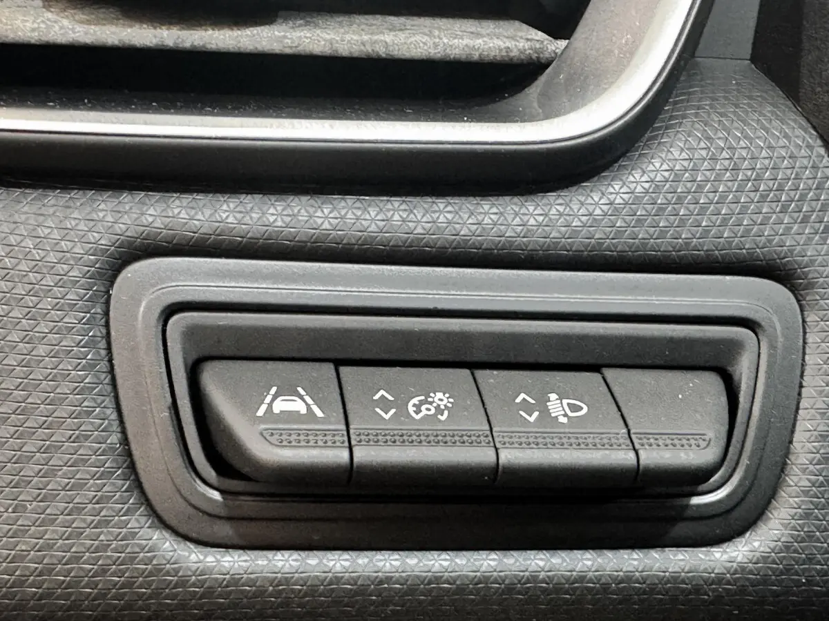 Gros plan sur les boutons de réglage des aides à la conduite et des phares dans une Renault Clio Business gris clair de 2020.